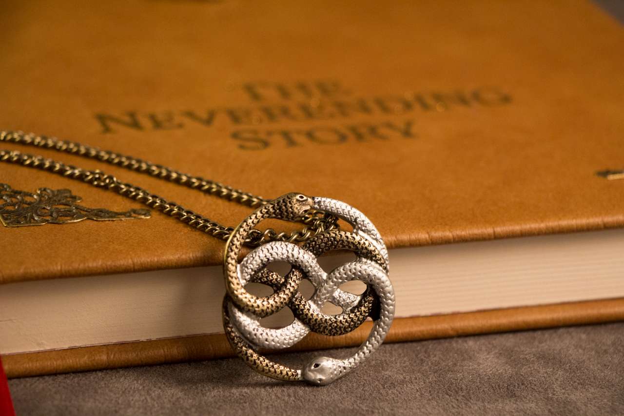 a medallion of two snakes eating each other leaning on the book the neverending story